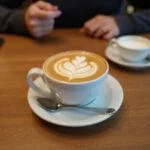 Beautifully presented cafe flat white on a wooden table, perfect for coffee lovers.