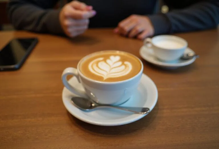 Beautifully presented cafe flat white on a wooden table, perfect for coffee lovers.
