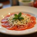 Finished carpaccio de calabacin garnished with cheese and herbs, ideal for a refreshing dish.