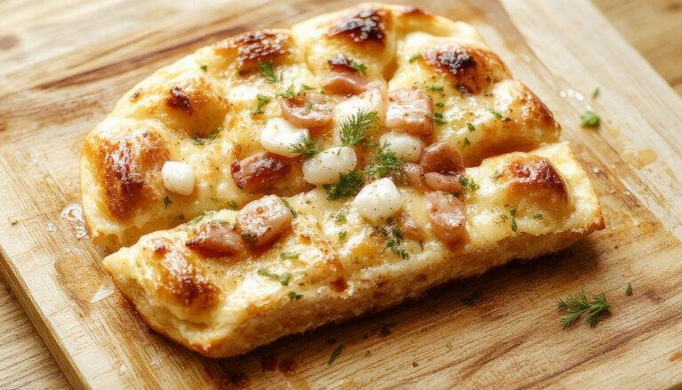 Focaccia italiana dorada, cubierta con ramitas de romero fresco y cristales de sal gruesa, presentada en un plato de madera con una textura crujiente y burbujas en la superficie.
